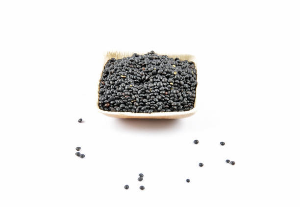 Beluga lentils in bamboo bowl on white background