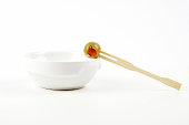 Olive with paprika on wooden skewer in porcelain bowl on white background