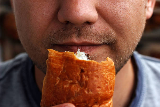 a man eats a bun, a man's mouth bites a bun close-up, nutrition concept