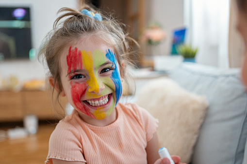 Portrait of an adorable Caucasian girl with a multicoloured face paint on