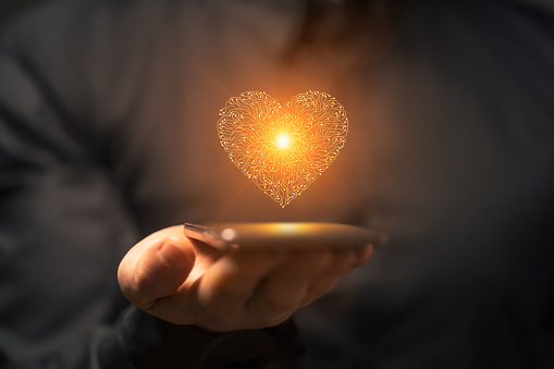 Artificial intelligence heart symbol on a smartphone held by a man. This file is cleaned and retouched.