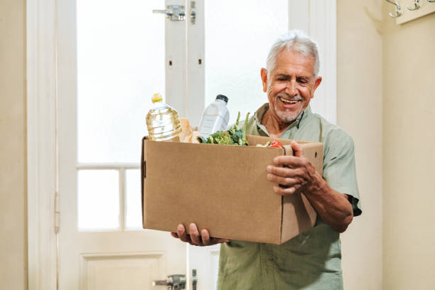 istock happy senior man open carrying shopping box with groceries 2010304568