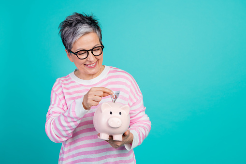 Photo of positive good mood woman dressed pink pullover collecting banknotes money box empty space isolated teal color background.