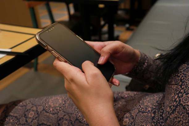 istock female hand holding smartphone in a restaurant. selective focus 2010308362