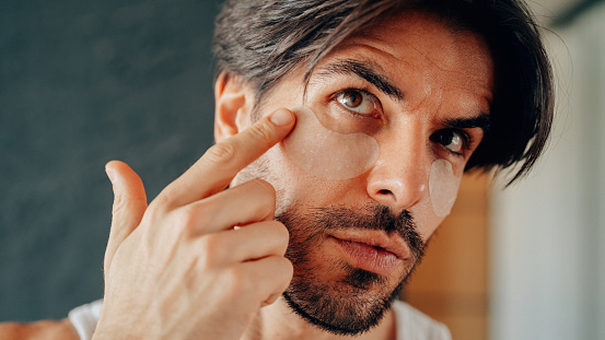 Man at home applying under eye patches for dark circles