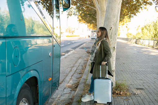 young girl with suitcase waiting for the bus
