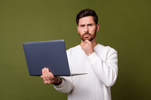 Photo of successful serious man wear trendy white clothes hold modern gadget wireless netbook isolated on khaki color background.