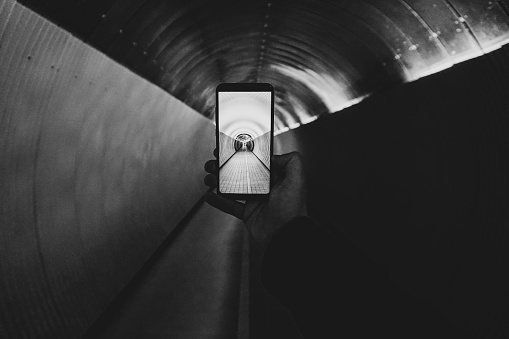 Cropped hand holding a mobile phone in a tunnel