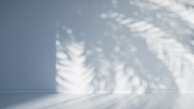 Shadow of palm leaves on an empty light blue room wall