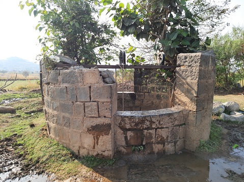 an old water well completely made of stone use to lift drinking water using pulley-rope system.