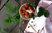 strawberry plant background. Ripe red organic berries in a bowl. Selective focus. The harvest eco-friendly fruits.