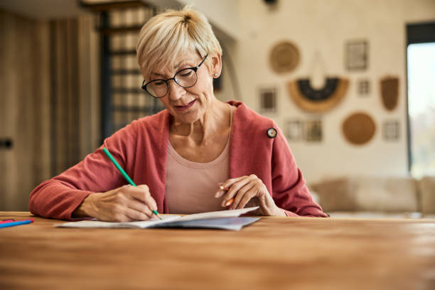 istock A senior woman, holding and using a crayon, coloring the coloring book. 2010354251