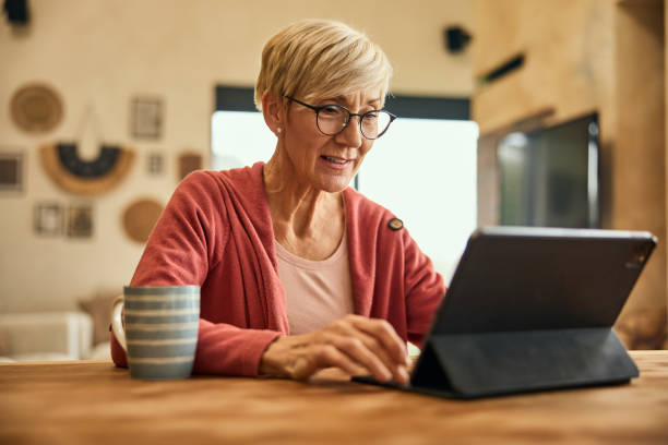 istock A senior woman sitting at home and using a digital tablet while drinking a cup of coffee. 2010354255