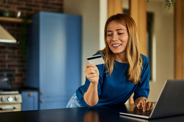 istock A smiling blonde woman, using and reading information from the credit card., 2010361786