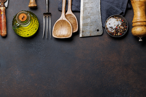 Culinary essentials: Diverse cooking utensils and spices on stone table. Flat lay with copy space