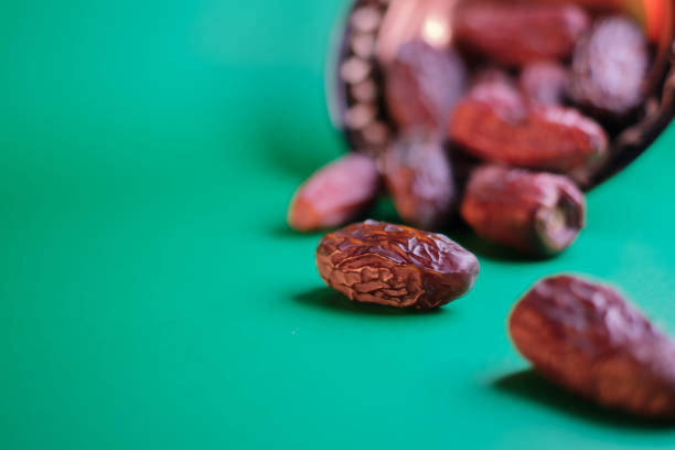 Concept idea image for the month of Ramadan. One of the dates on the green background is sharpened. Blurred background. Selective focus.