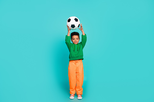 Full length photo of funny cute boy professional football player training world cup league isolated on cyan color background.