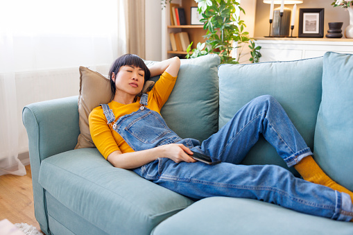 Beautiful woman taking a nap on living room couch while relaxing at home and enjoying her leisure time