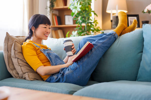 istock Woman drinking coffee and reading a book at home 2010394579