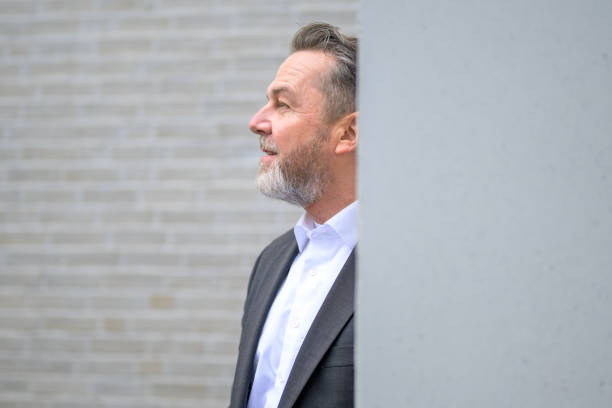 istock Attractive sixty year old gray man in front of a white brick wall looking to side 2010397833