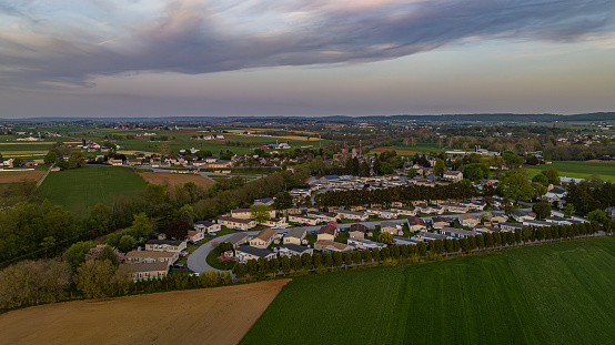 Overcast Skies Overlook A Sprawling Landscape Of Agricultural Fields, Clustered Housing, And Winding Roads At Dusk.