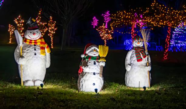 istock Three Illuminated Snowman Figures With Scarves And Hats Holding Brooms, Displayed At Night 2010406825