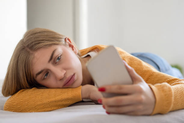 istock Woman lying on bed while scrolling through social media on phone 2010424534