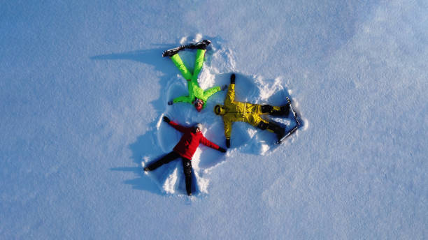 istock Winter activities in nature. Snow angel. Three persons, fun 2010427873
