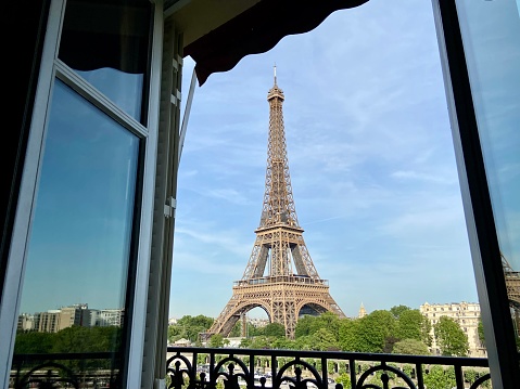 View of the Eiffel Tower from an open balcony window in an apartment in the 16th arrondissement on a sunny afternoon