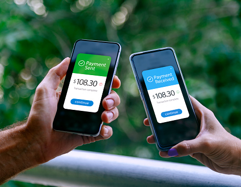 Two smartphones held by a woman and a man showing sending and receiving payments through a digital wallet application on a mobile phone. Bank transfer concept. Digital money.