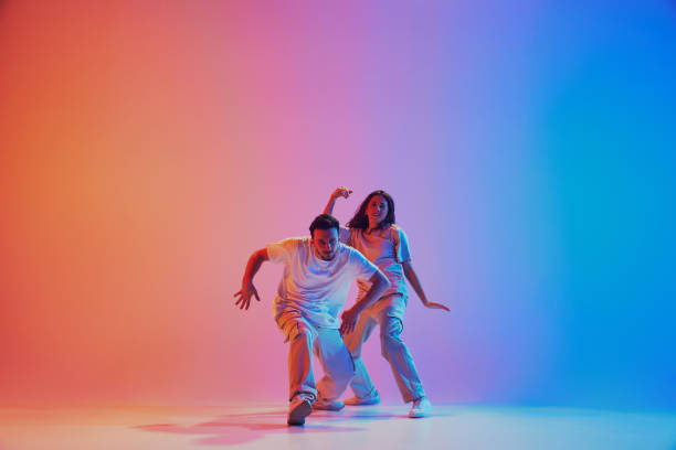 istock Dynamic lifestyle. Dancers performing hip hop, freestyle in neon lights against gradient studio background. 2010497883