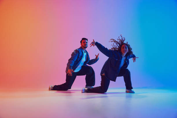 istock Two young duo dancers training dance moves in motion against gradient studio background in neon light, filter. 2010497886