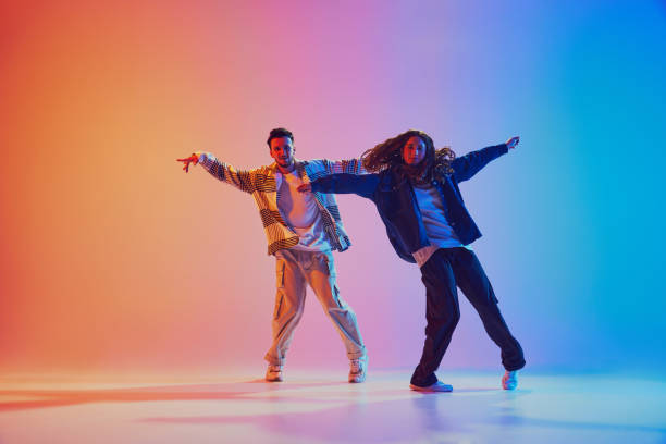istock Dynamic photo of two fashion dressed people, dancing in motion against gradient studio background in neon light, filter. 2010497914