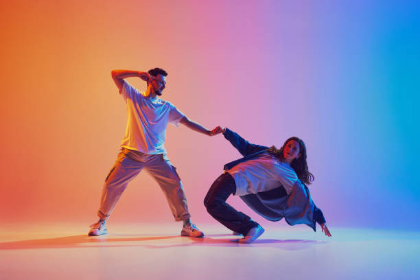 istock dynamic portrait of man and woman dancing in pair in motion against gradient studio background in neon light, filter. Performance 2010497917