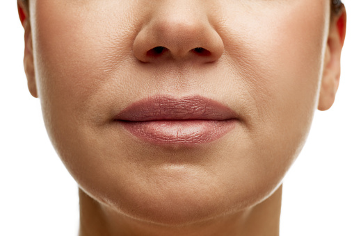 Cropped portrait of middle-aged woman with full moisturized pink lips with natural gloss and well-kept skin. Prevention of nasolabial folds. Concept of facial treatment, spa, cosmetology, anti-aging.