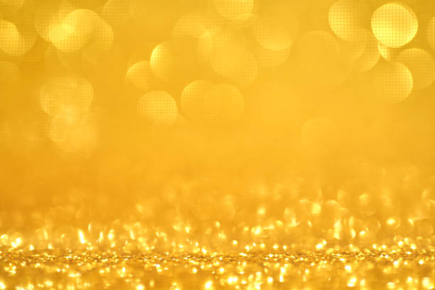 Defocused golden sequin light. Fancy gold glitter sparkle background. Studio shooting of a creative bright yellow color background. It is textured color gradient. There are no text and no people, and have copy space for design. Its Suitable for commercial use. Christmas, New Year, Diwali festive celebrations themed backgrounds, wallpapers, templates for greeting cards, banners and posters and wrapping paper is apt.