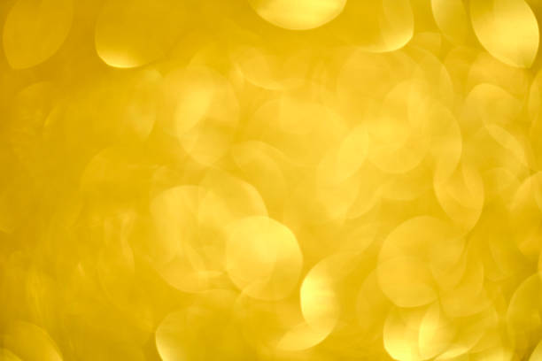 Defocused golden sequin light. Fancy gold glitter sparkle background. Studio shooting of a creative bright yellow color background. It is textured color gradient. There are no text and no people, and have copy space for design. Its Suitable for commercial use. Christmas, New Year, Diwali festive celebrations themed backgrounds, wallpapers, templates for greeting cards, banners and posters and wrapping paper is apt.