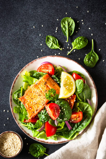 istock Green salad with salmon fillet on black. 2010553362