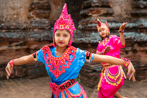 Young Burmese girls with thanaka face paint dancing in the ancient temple of Bagan, Myanmar (Burma)