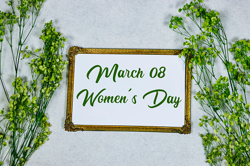 happy women's day on golden picture or photo frame mockup with green baby's breath, gypsophila on gray grunge background