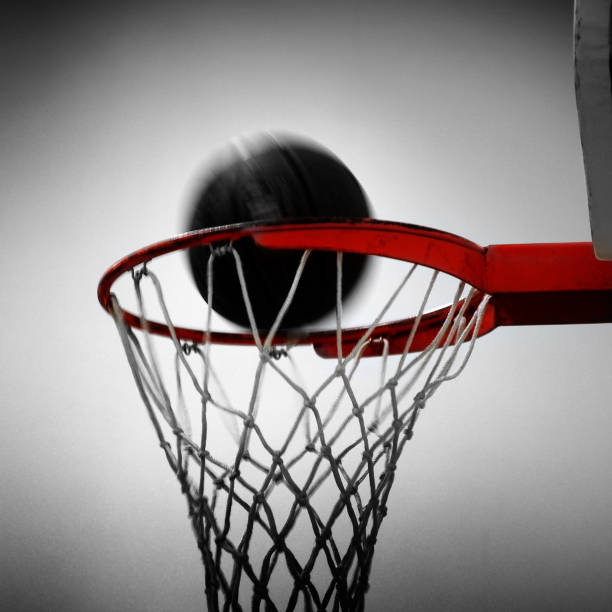 A young Asian woman, dressed in a red basketball jersey, is holding a basketball and pointing with her right index finger.  She appears focused and determined, embodying the spirit of a dedicated athlete. The image highlights the passion and commitment associated with the sport of basketball.