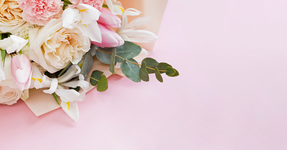 Horizontal close up of floral bunch of soft pink and white old fashioned roses buds peonies and green leaves