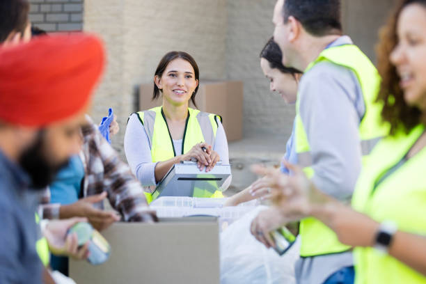 istock Female supervisor talks with male volunteer while others sort donations 2010606459