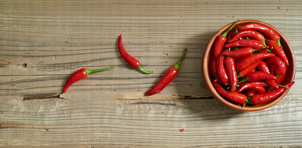 Red hot chili pepper with bowl on old wooden background.