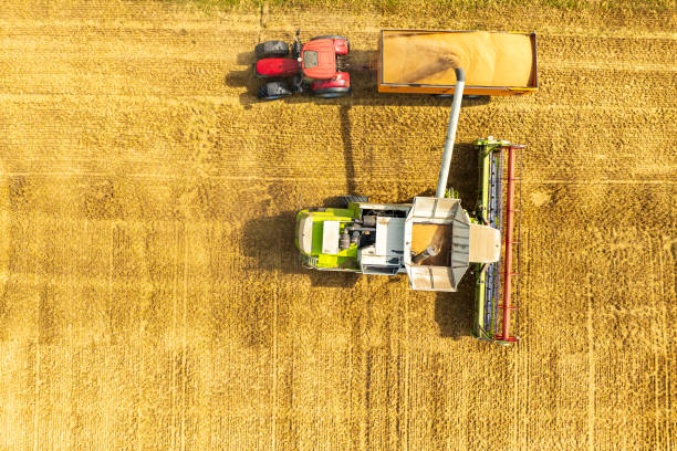 istock Combine harverster loading the harvest into a hauler pulled by a tractor 2010665566