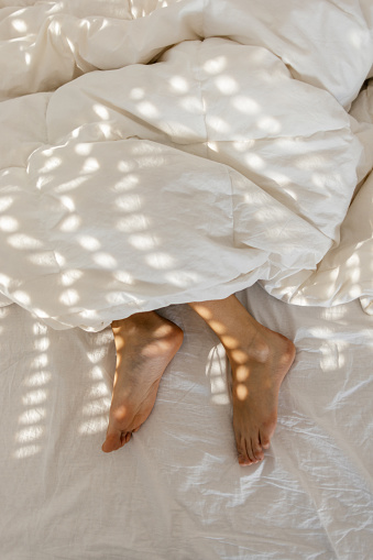 Young woman sleeping in her bed, in the photo are her feet, not covered with duvet