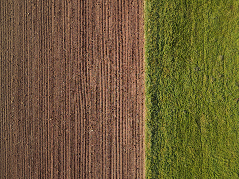 View from above of farm fields with soil and grass in the countryside in summer