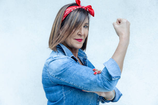 Modern day interpretation of the 'Rosie the Riveter' with a stylish woman showing her bicep in a denim outfit and red headscarf