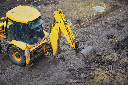 A yellow excavator is working on a construction site, the initial stage of construction, earthworks