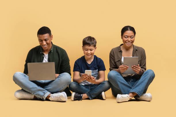 istock Happy black family of three holding using different electronic devices 2010725070